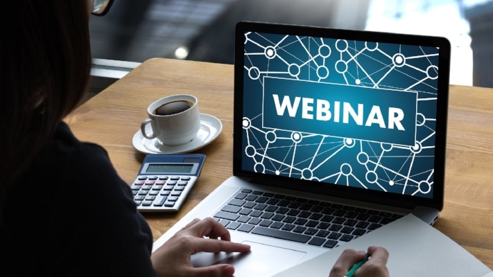 Woman looking at laptop with webinar portal on it, ready to take notes