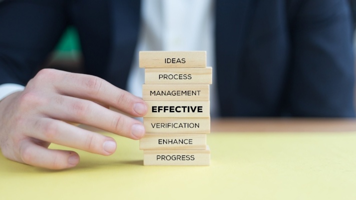 Man with stack of blocks with words like EFFECTIVE on them