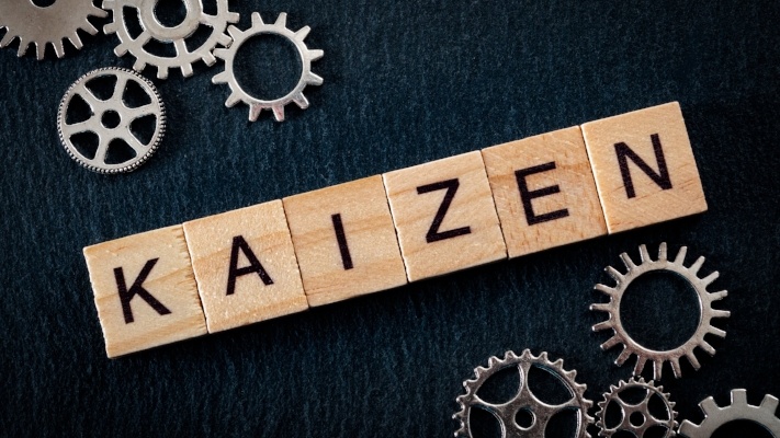 Teamwork in business and the concept of continuous improvement, with tiles spelling Kaizen